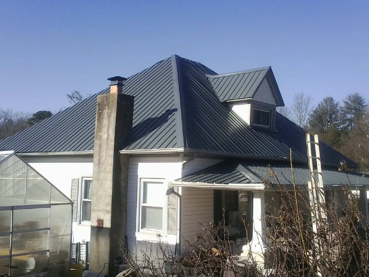 Dark blue standing seam metal roof on a white farmhouse with dormer — Slate & Tile Roof Repair by Roofing Brothers in Dellroy