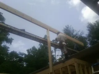 Carpenter setting a ridge beam over a new addition frame — Ice Dam Removal by Roofing Brothers in Dellroy