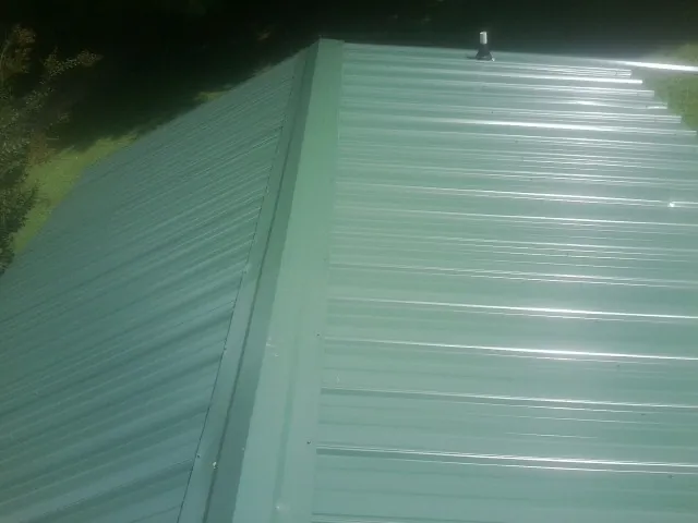 New green metal panels meeting at the ridge of a roof — Flat Roof Repair work by our crew in Dellroy