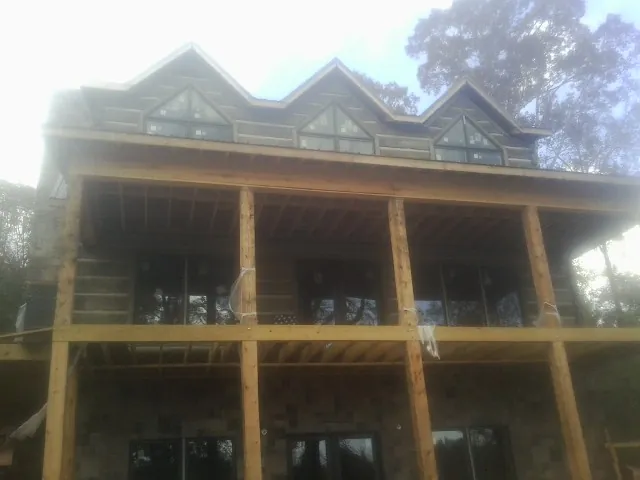 Dormers and porch framing on a large log home under construction — Roof Coating work by our crew in Dellroy