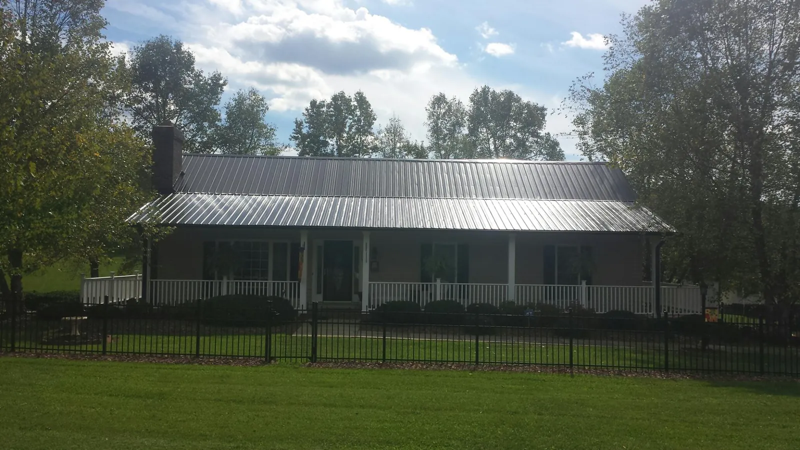 Gray metal roof on a brick ranch with a full width front porch — Gutter Guard Installation work by our crew in Dellroy