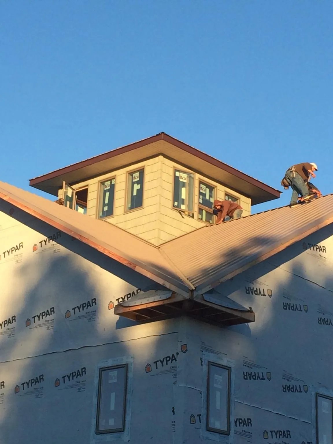Roofers working around a rooftop cupola on a new metal roof at sunset — Roof Waterproofing in Dellroy by Roofing Brothers